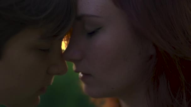 Two serious women with closed eyes enjoying sunset in front of high grass almost kissing with lips close to each other — Stock Video