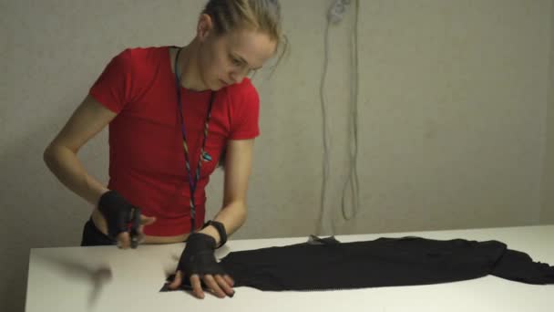 Diseñadora de moda cyber punk en el trabajo en su patrón de corte de estudio - Mujer blanca caucásica con camiseta roja y guantes negros con tijeras colgando sobre su pecho — Vídeos de Stock