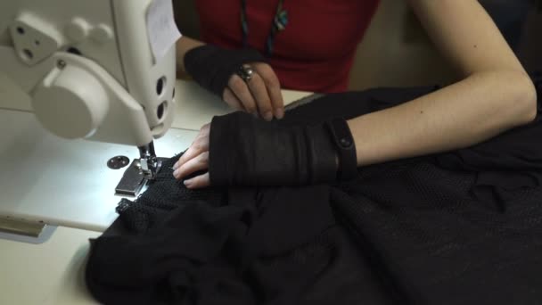 Diseñadora de moda cyber punk en el trabajo en su estudio de costura con máquina - Mujer blanca caucásica con camiseta roja y guantes negros con tijeras colgando sobre su pecho — Vídeo de stock