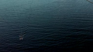 Hava: Güzel 4k küçük bir tekne su taşıma aşağıdaki - Yukarıdan Daugava nehir rüzgarlı rüzgarlı hava bir kuş bakışı görünümü - Sunset drone üst görünümü