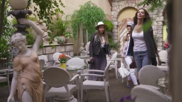 Tre resande tjej vänner lämnar italiensk restaurang med lätta ryggsäckar utforska Riga City-Travel turism koncept efter överföring från flygplats-bär hattar och jeans — Stockvideo
