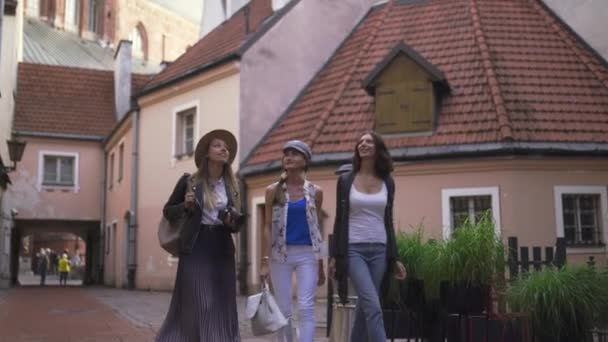 Three traveling girl friends with light backpacks walking exploring Riga city - Travel tourism concept after transfer from airport - Wearing hats and jeans — Stock Video