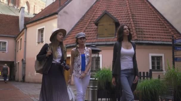 Три подорожі дівчину друзів з легкими рюкзаками прогулянки по місту Рига-туристичний туризм концепція після передачі з аеропорту-носіння капелюхи і джинси — стокове відео