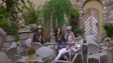 Riga şehrini keşfeden hafif sırt çantaları ile İtalyan restoranında oturan üç seyahat eden kız arkadaş - Havaalanından transfer den sonra seyahat turizm konsepti - Şapka ve kot pantolon giyiyor