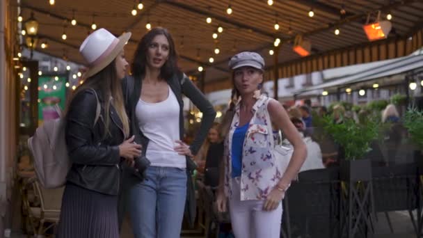 Болтовня и смех Три путешествующие девушки с легкими рюкзаками, знакомящими с городом Рига - Концепция туристического путешествия после трансфера из аэропорта - Ношение шляп и джинсов — стоковое видео