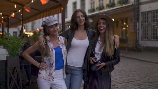 Chatting and laughing Three traveling girl friends with light backpacks exploring Riga city with police passing by - Travel tourism concept after transfer from airport - Wearing hats and jeans — Stock Video