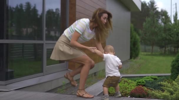 Genç anne oyun ve oyuncaklar ile bir bahçede onun bebek erkek erkek kardeşi ile eğlenmek - Aile değerleri sıcak renk yaz sahnesi — Stok video