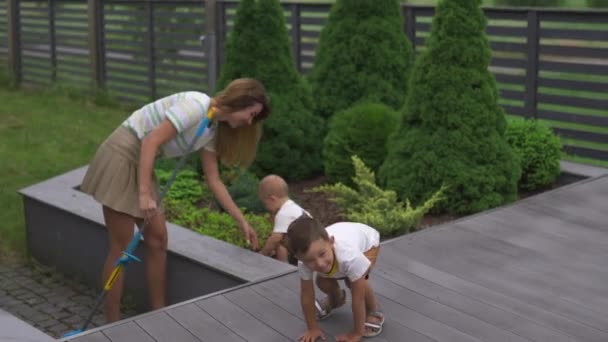 Ung mamma leker och ha kul med sin baby pojke son bröder i en trädgård med leksaker-familjens värderingar varm färg Sommarscen — Stockvideo