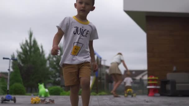 Jonge moeder spelen en plezier met haar baby jongen zoon broers in een groene tuin met fietsen-familie waarden warme kleur zomer scène — Stockvideo