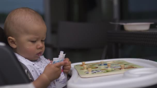 Junge Mutter füttert ihren kleinen Sohn im Kindersitz - Familie schätzt warme Farbe im Sommer — Stockvideo