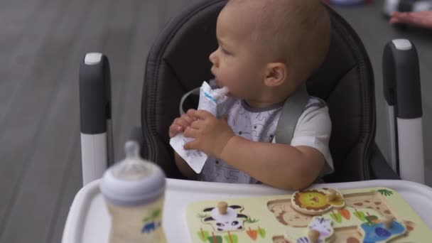 Cara de cerca divertido bigote blanco: Madre joven alimentando a su hijo niño niño sentado en un asiento para niños - Familia valores de color cálido escena de verano — Vídeo de stock