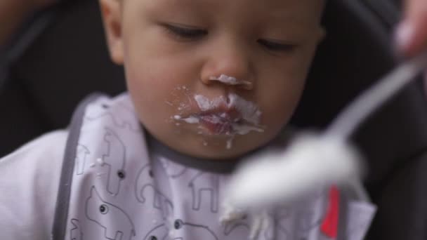 Gesicht aus nächster Nähe lustiger weißer Schnurrbart: junge Mutter füttert ihren kleinen Sohn im Kindersitz - Familie schätzt warme Farbe — Stockvideo