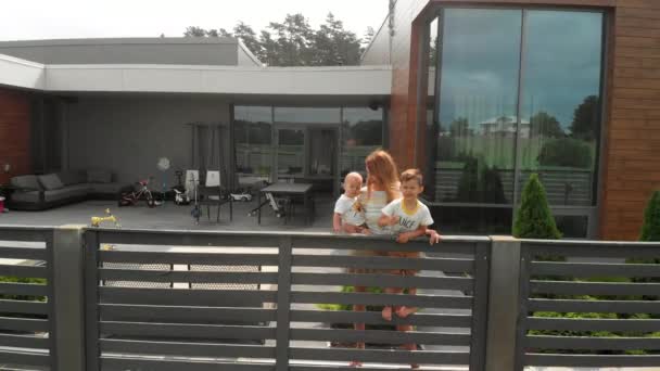 Aérea: Madre joven con sus hermanos hijo bebé durante su tiempo libre en su jardín - Valores de la familia de color cálido escena de verano drone plano superior desde arriba — Vídeos de Stock