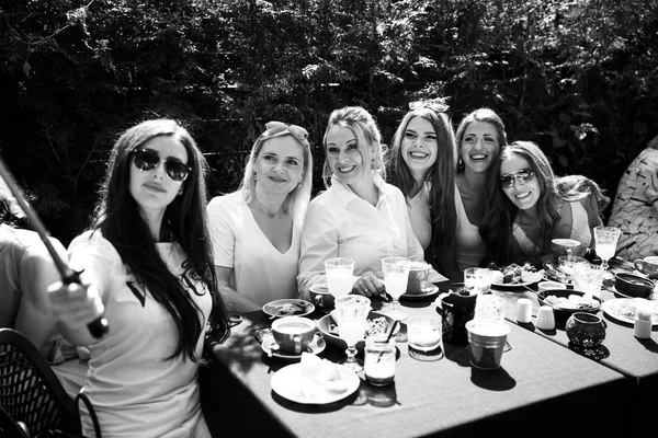 Groupe d'amis en blanc prenant le petit déjeuner dans le jardin à table avec de la nourriture et de communiquer, concept riant — Photo