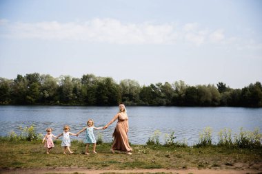 Anne karahindiba üfleme bir parkta onun bebek kız ile kaliteli komik oyun zamanı olan - Genç sarışın hippi - Kızları çilek baskı ile benzer elbiseler giymek - Aile değerleri