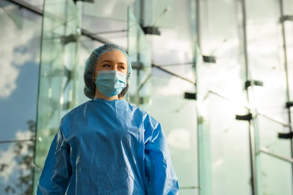 Una doctora o enfermera confiada en máscara quirúrgica y gorra quirúrgica te mira — Foto de Stock