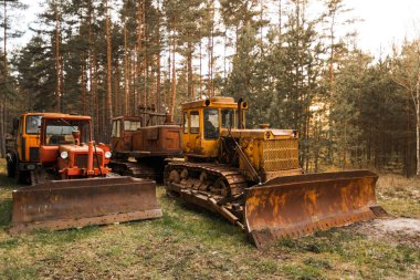 Kocaman yük kovalarıyla terk edilmiş eski paslı traktörler.
