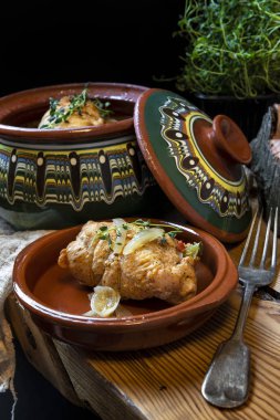 Ahşap masa, siyah arka plan üzerine bir rustik taş kase Kızartma tavuk rulo