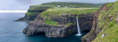 Gasadalur Köyü Panoraması ve Kuzey Atlantik Okyanusu 'nun yukarısındaki inanılmaz şelale Mulafossur. Faroe Adaları. Danimarka.