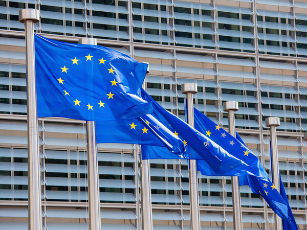 Европейские флаги перед зданием штаб-квартиры Европейской комиссии в Брюсселе, Бельгия, Европа
