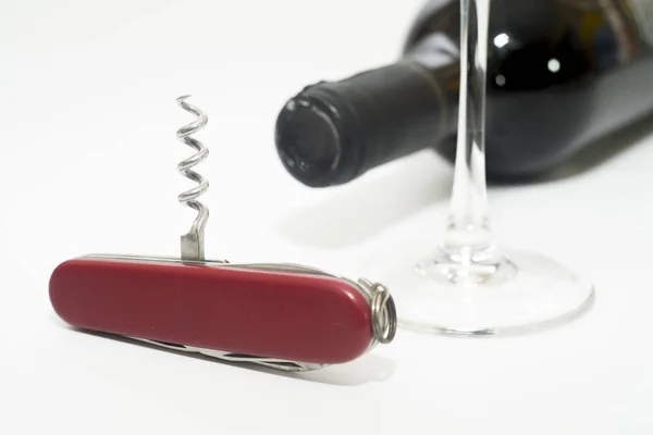 Folding knife with wine opener, glass and wine bottle on a white background