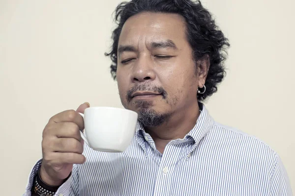 Чоловік п'є каву в чашці, посміхається і щасливий — стокове фото