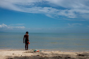 Genç çocuk sahilde tek başına duruyor..