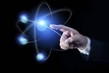 İş adamı eli yaratıcı atomu işaret ediyor. Nükleer füzyon konsepti, sonsuz enerji, ucuz elektrik, yenilikçi teknolojiler, gelecek teknolojileri. Bilim ve gelecek kavramı