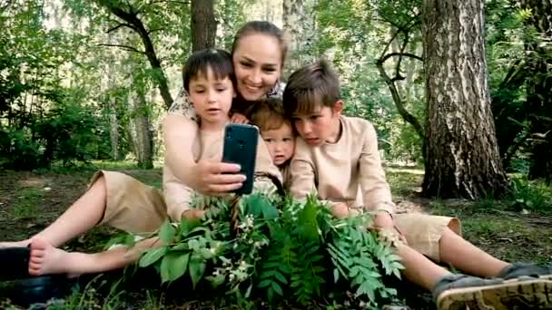 Annem ve üç oğlum selfie çekiyorlar. Parkta yürü. Yaz. Aktif aile tatili. Mutlu, komik, çocukluk, tasasız. Güneş, çimen, piknik. — Stok video