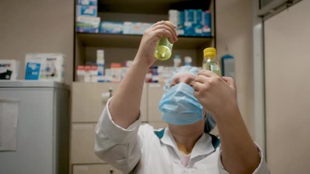 Mujer farmacéutica de 40-50 años en una farmacia examina una botella en una farmacia. Los médicos están considerando medicamentos. Cirujano especialista en la clínica mira la medicina. Farmacia venta de medicamentos — Vídeo de stock