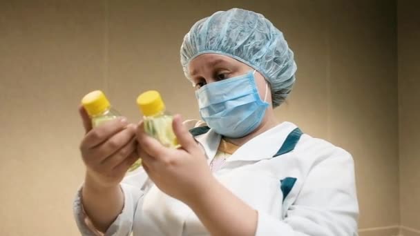 Mujer farmacéutica de 40-50 años en una farmacia examina una botella en una farmacia. Los médicos están considerando medicamentos. Cirujano especialista en la clínica mira la medicina. Farmacia venta de medicamentos — Vídeo de stock