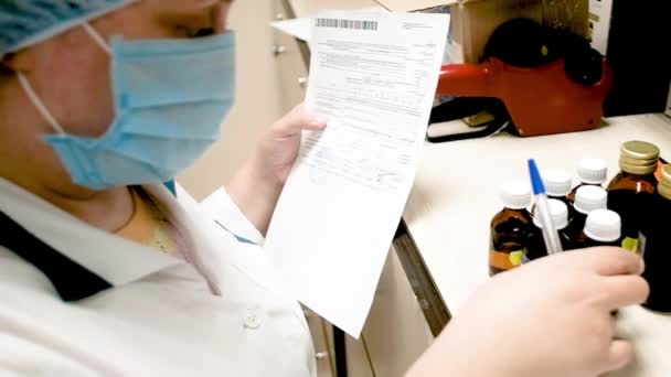 Pharmacienne femme de 40 à 50 ans en pharmacie examine une bouteille dans une pharmacie . — Video