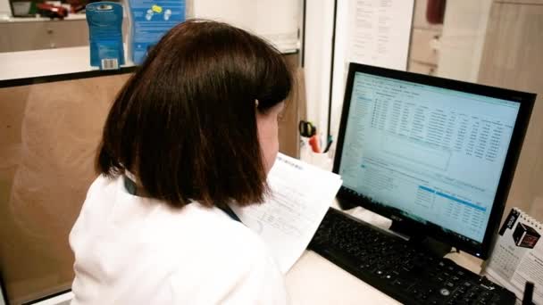 Ung asiatisk farmaceut kvinna som innehar dator tablett använder för att kontrollera läkemedelsdetaljer på en låda i apotek apotek apotek apotek apotek apotek. — Stockvideo