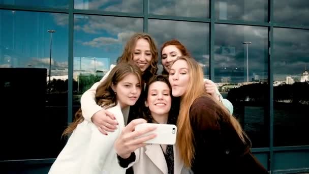 Vacaciones y el concepto de turismo hermosas chicas tomando selfie al aire libre en la ciudad .five niñas en el teléfono inteligente cerca de las ventanas de vidrio. juventud, juventud. caminar en la primavera . — Vídeo de stock