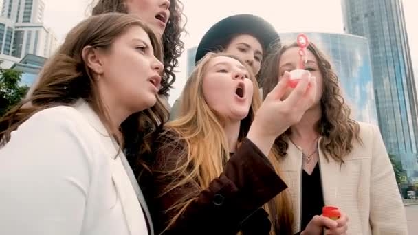 Las chicas hacen burbujas en la ciudad. concepto de vacaciones y turismo - chicas hermosas. Camina al aire libre. Cinco niñas de 20 a 25 años, jóvenes. Feliz verano. . — Vídeo de stock