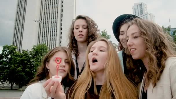 Las chicas hacen burbujas en la ciudad. concepto de vacaciones y turismo - chicas hermosas. Camina al aire libre. Cinco niñas de 20 a 25 años, jóvenes. Feliz verano. . — Vídeo de stock