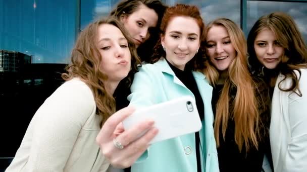 Urlaub und Tourismuskonzept - schöne Mädchen beim Selfie im Freien in der Stadt. Fünf Mädchen auf dem Smartphone in der Nähe von Glasfenstern. Jugend, Jugend. Spaziergang im Frühling. — Stockvideo