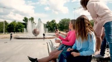 Genç ve güzel kızlar şehirde sabun üflüyorlar. Akıllı telefondan çekilmiş bir fotoğraf. Temiz havada yürü. 20-25 yaşlarında beş kız. Kız arkadaşlar tanışma konsepti