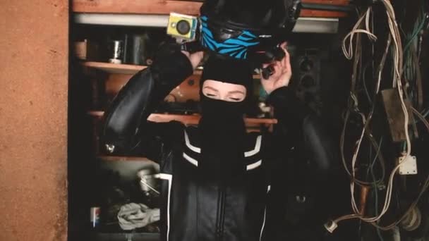 Schöne Motorradfahrerin setzt einen Helm in der Garage auf. Das Konzept der Sicherheit, eines aktiven Lebensstils, Geschwindigkeit und Freiheit. Modische Motorradausrüstung. Schöne Mädchen 20-25 Jahre alt. — Stockvideo