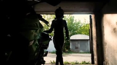 Garajda motosikletli güzel bir kadın. - Kapıyı açar. Güvenlik kavramı, aktif yaşam tarzı, hız ve özgürlük. Moda motosiklet ekipmanları. 20-25 yaşlarında tatlı bir kız..