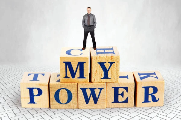 Self Confident adult Caucasian man stands on the top of heap of wooden blocks with a text My Power