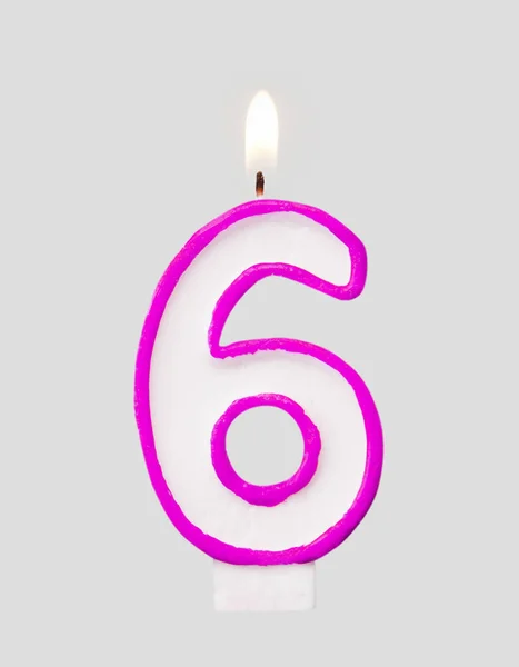 Burning wax candle for a birthday cake in the form of number six