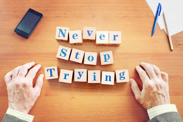 Never stop trying. Businessman made text from wooden cubes