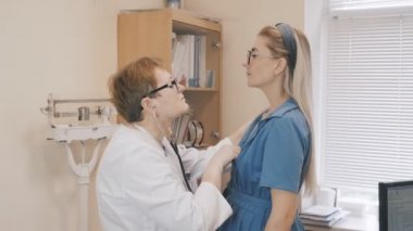 Hekim, steteskop kullanarak hastanın akciğerlerini dinleyip doktoru ziyaret ediyor..