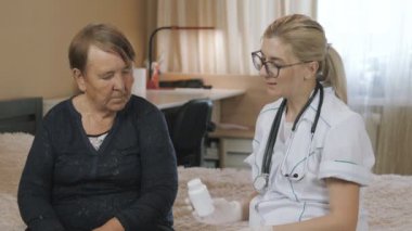Kıdemli kadın ve doktor. Tıbbî danışma büyükannesi evde. İlaç haplarını yaşlı hastaya açıklamak.