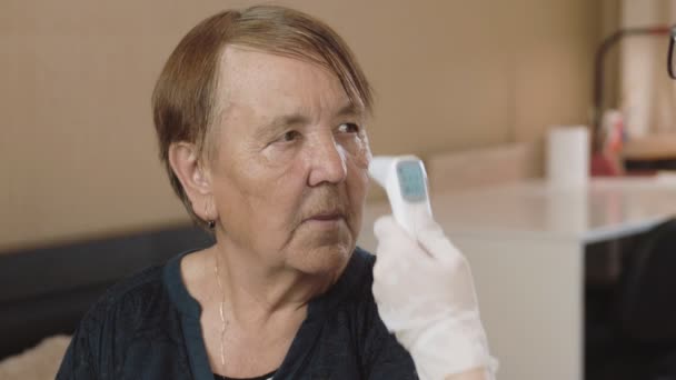 Lekarz Mierzy Temperaturę Starszej Kobiety Pomocą Elektronicznego Termometru Kwarantanna Domowa — Wideo stockowe