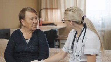 Yaşlı kadın ve doktor. Ev ziyareti. Tıbbî danışma büyükannesi evde. Sıcaklığı ölçer.