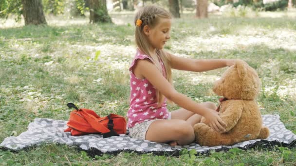 Parkta yürüyen mutlu küçük kız. Doğada oyuncak ayıyla oynamak. Mutlu çocukluk. — Stok video