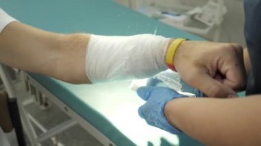 Bandajlı el. Travmatoloğu ziyaret ediyorum. Doktor hastanın eline bandaj uyguluyor..