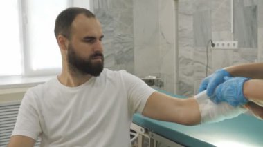 Doktor hastanın eline bandaj uyguluyor. Travmatoloğu ziyaret ediyorum. Sargı bezi..